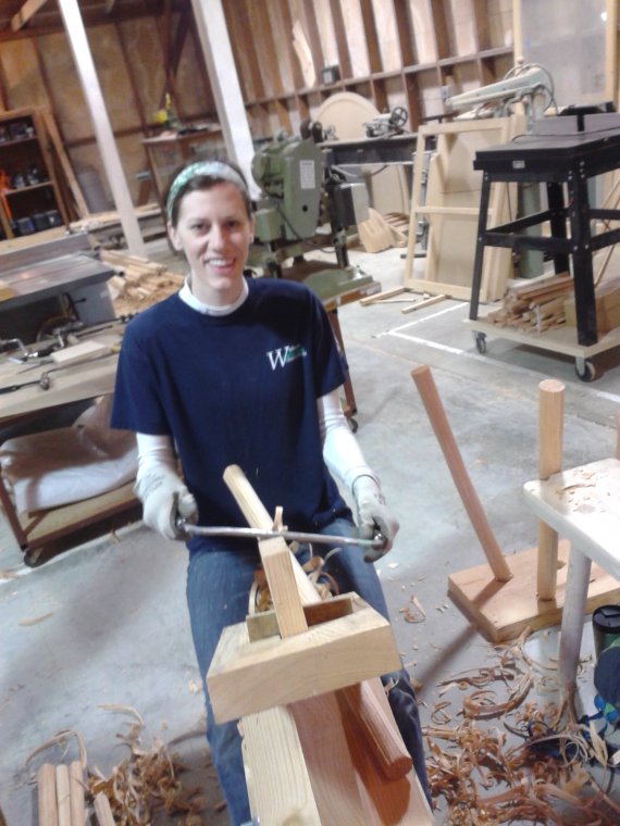 Sara, using the shave horse and draw knife to shape a stool leg  